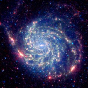 Spitzer's view, taken in infrared light, reveals the galaxy's delicate dust lanes as yellow-green filaments.